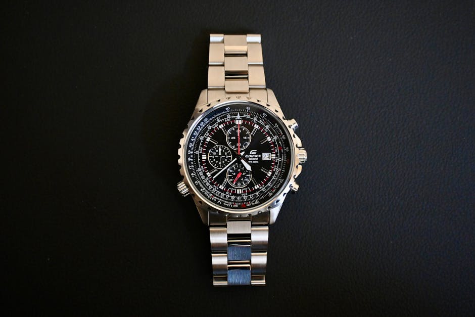 Elegant stainless steel pilot watch with chronograph and slide rule on black background.